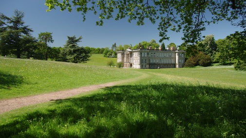 A view of the east side of the house surrounded by green trees and flowering meadows